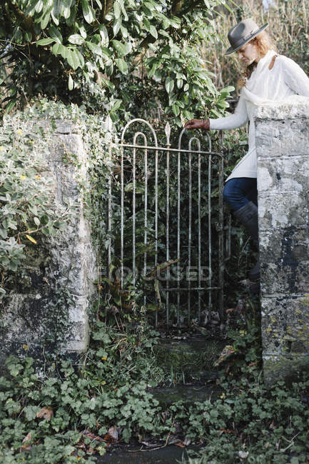 Mulher abrindo um portão de jardim — Fotografia de Stock