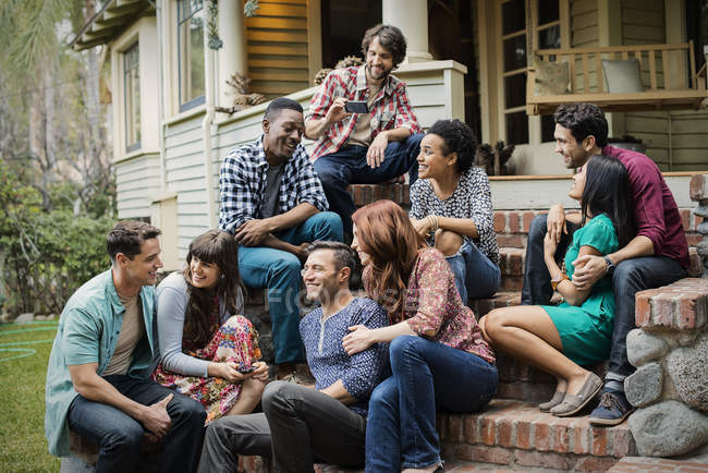 Friends sitting on the steps of a house porch — Stock Photo