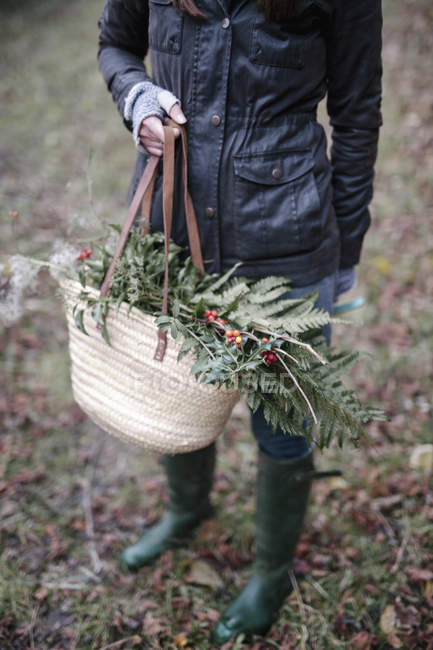 Woman carrying basket of foliage — Stock Photo