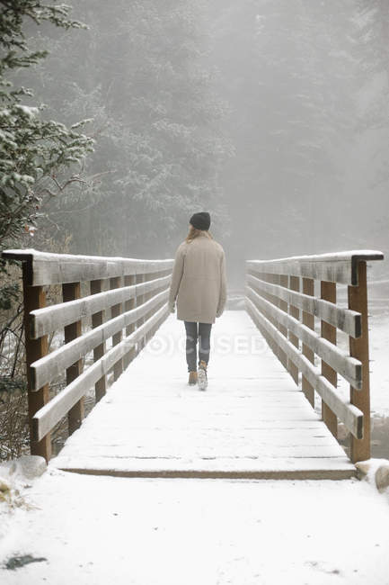 Frau läuft auf Fußgängerbrücke im Schnee. — Stockfoto