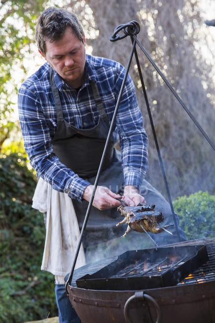 Man lifted game birds off the griddle — Stock Photo