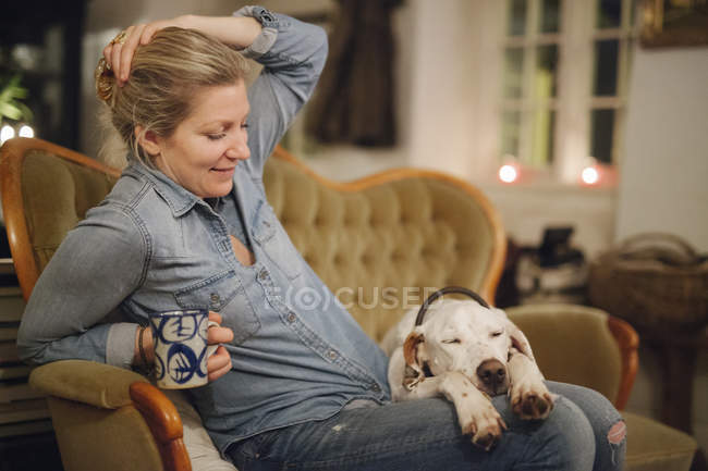 Donna seduta su un divano con cane — Foto stock