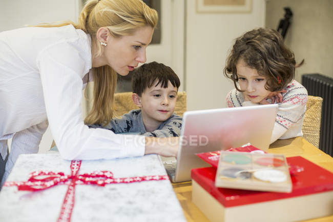 Les enfants et leur mère regardant un ordinateur portable — Photo de stock
