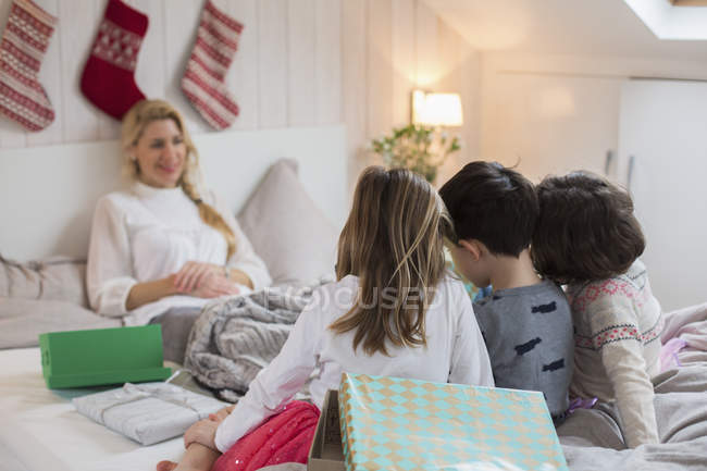 Famille assise au lit le matin de Noël — Photo de stock