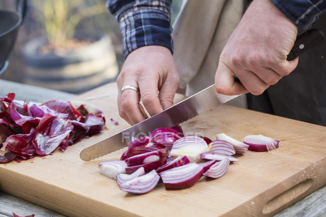 Uomo affettare cipolle rosse . — Foto stock