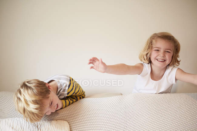 Crianças brincando atrás de um sofá — Fotografia de Stock