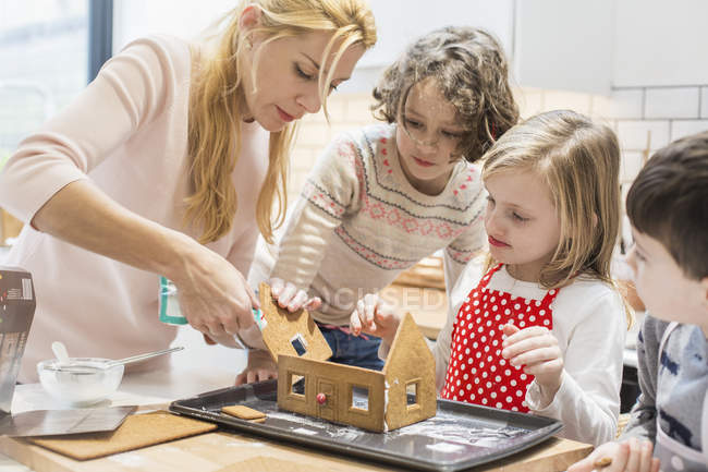 Family creating a baked gingerbread house. — Stock Photo