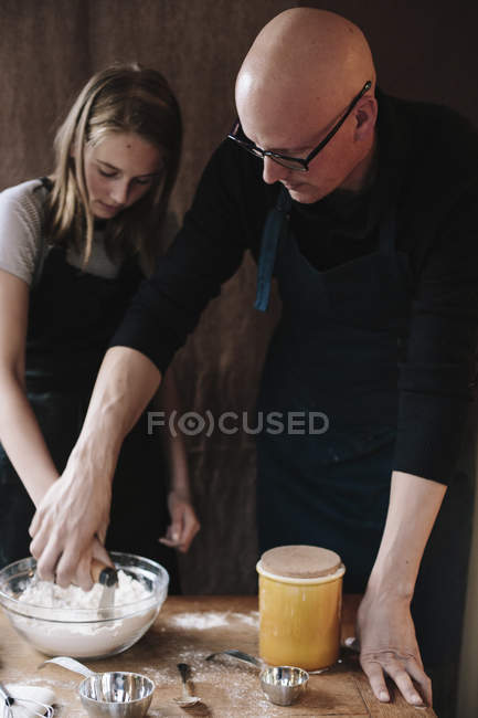 Hombre y joven chica mezclando ingredientes - foto de stock