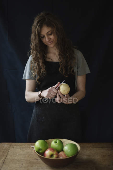 Mulher descascando uma maçã com uma faca . — Fotografia de Stock