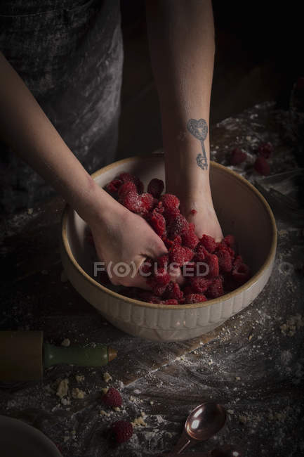 Mulher preparando framboesas frescas na tigela — Fotografia de Stock