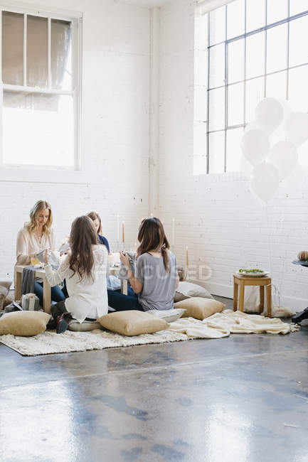 Frauen am niedrigen Tisch auf Kissen. — Stockfoto