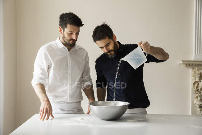 Bakers pouring water into bowl. — Stock Photo