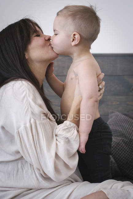 Беременная женщина целует сына — стоковое фото