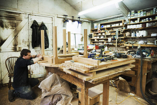 Mann arbeitet an der Sockelleiste eines Holztisches. — Stockfoto