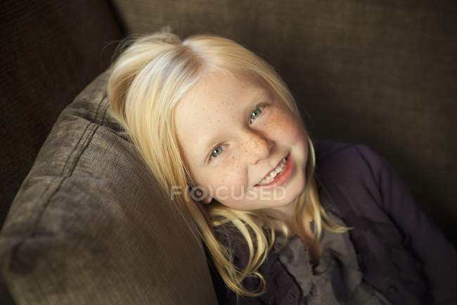 Chica sentada en el sofá - foto de stock