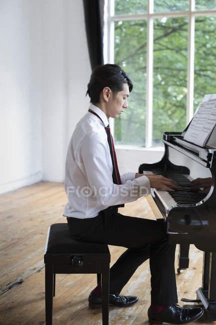 Homme jouant sur un piano à queue — Photo de stock