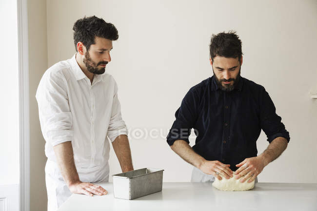 Dos panaderos de pie en una mesa - foto de stock