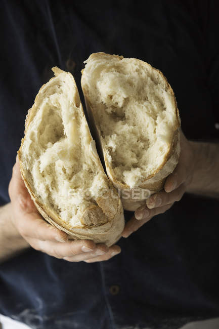 Panadero sosteniendo una barra de pan. - foto de stock