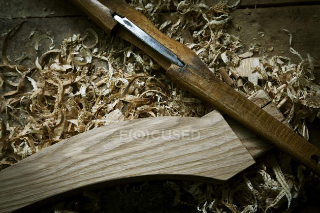 Cincel y objeto de madera con virutas de madera - foto de stock