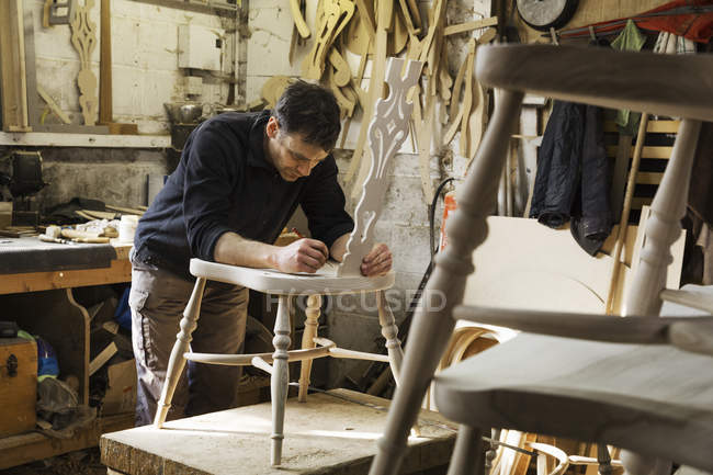 Man working on a wooden chair. — Stock Photo