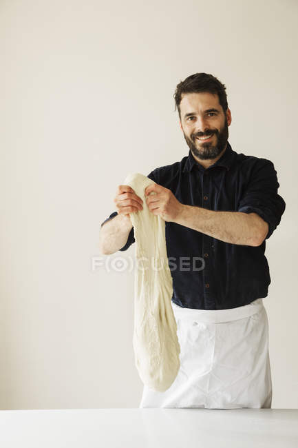 Baker holding up a bread dough — Stock Photo