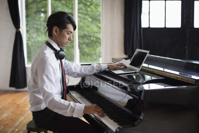 Homem sentado em um piano de cauda — Fotografia de Stock