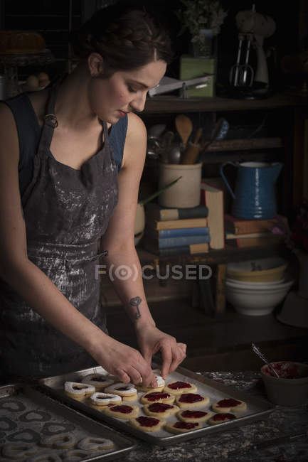 Woman in kitchen with baking tray of biscuits — Stock Photo