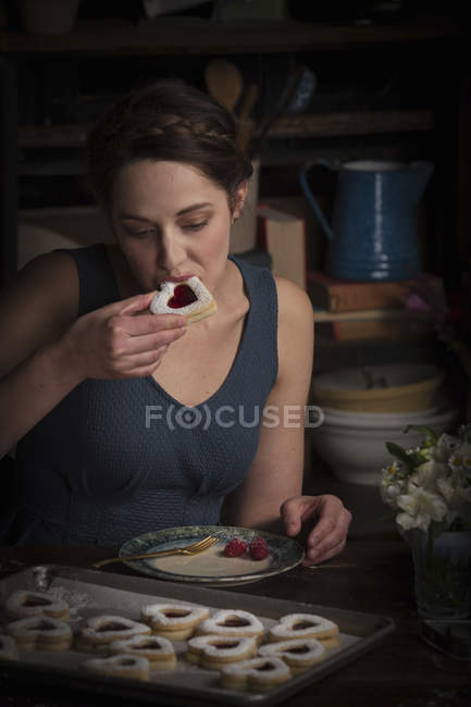 Woman eating heart shaped biscuit — Stock Photo