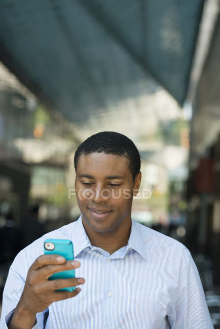 Businessman in open necked shirt checking phone — Stock Photo