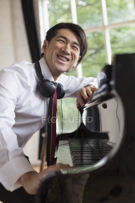 Улыбающийся человек, сидящий за роялем — стоковое фото