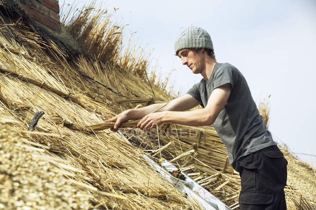 Young man thatching roof — Stock Photo