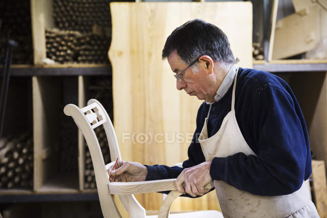 Man working on a wooden chair. — Stock Photo