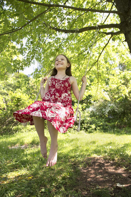 Girl on swing swinging from bough — Stock Photo
