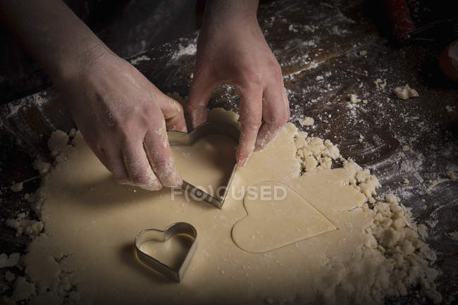Frau schneidet herzförmige Kekse aus — Stockfoto