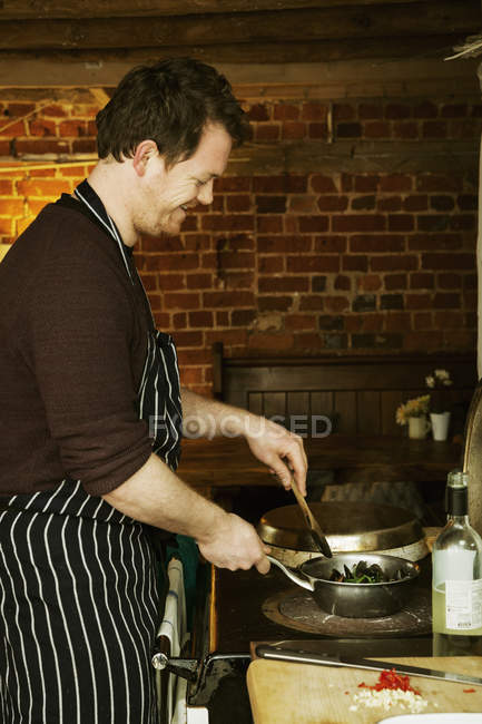 Homme cuisine moules noires dans une casserole . — Photo de stock