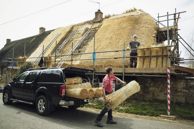 Thatcher unloading bundles of straw — Stock Photo