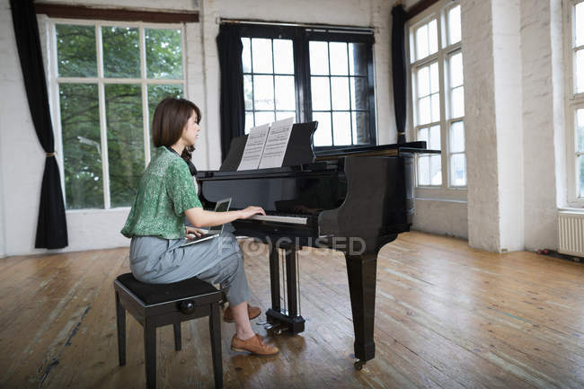 Mujer tocando en un piano de cola - foto de stock