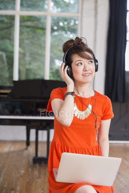 Mulher usando fones de ouvido no estúdio de ensaio — Fotografia de Stock