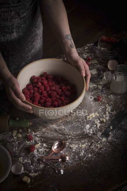Mains féminines tenant bol avec framboises — Photo de stock
