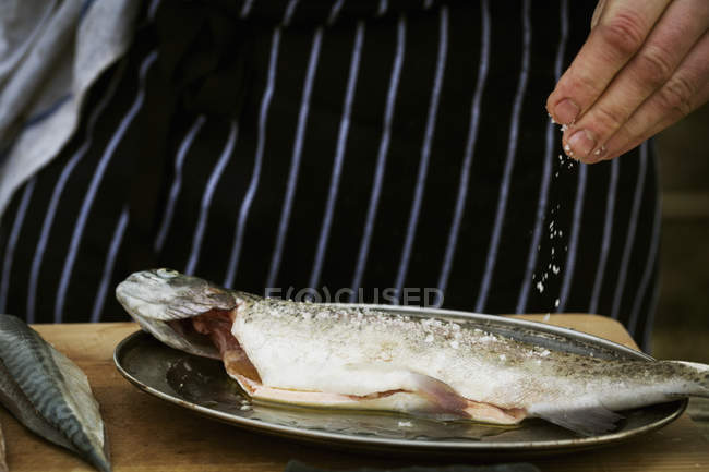 Salz auf einen frischen Fisch streuen. — Stockfoto