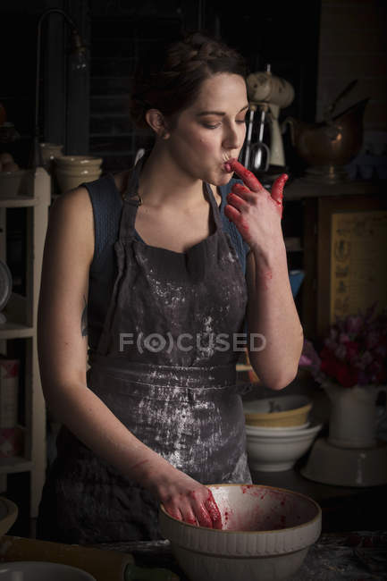 Woman licking finger with raspberry jam — Stock Photo