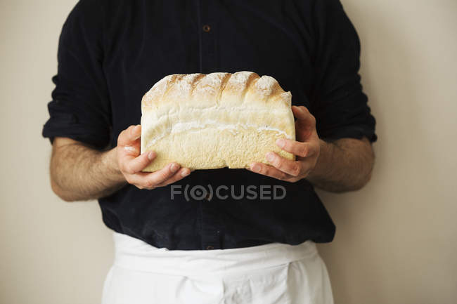 Baker holding a loaf of white bread. — Stock Photo