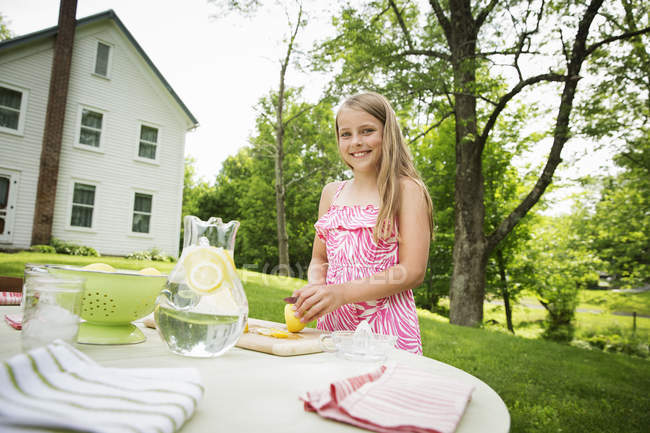 Mädchen schneidet Zitronen, um Limonade zu machen. — Stockfoto