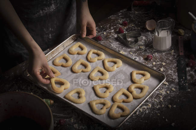 Frau arrangiert herzförmige Kekse — Stockfoto