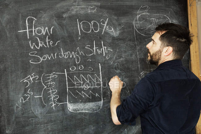 Baker standing in front of a blackboard — Stock Photo
