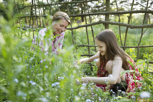 Mother and daughter picking flowers and plants — Stock Photo
