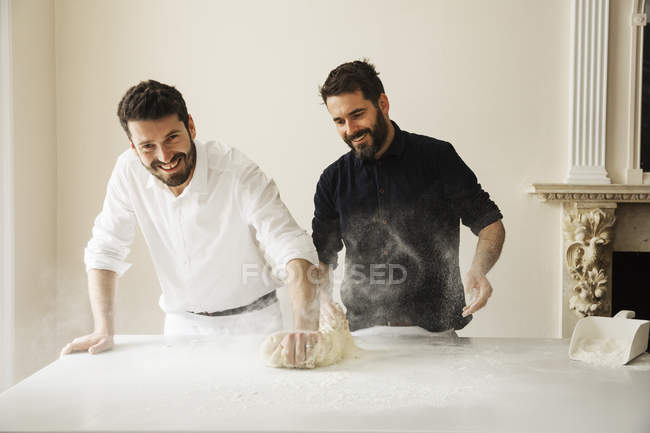 Boulangers époussetant la pâte à pain avec de la farine — Photo de stock