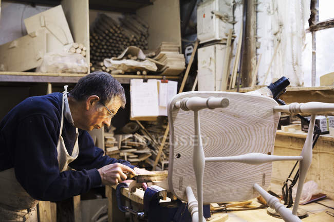 Homem trabalhando em uma cadeira de madeira — Fotografia de Stock