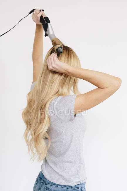 Mujer con el pelo rubio usando peine - foto de stock
