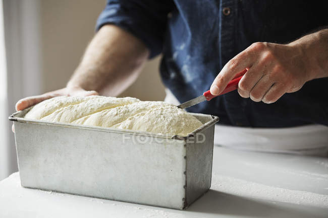 Bäcker schneidet Brotteig — Stockfoto